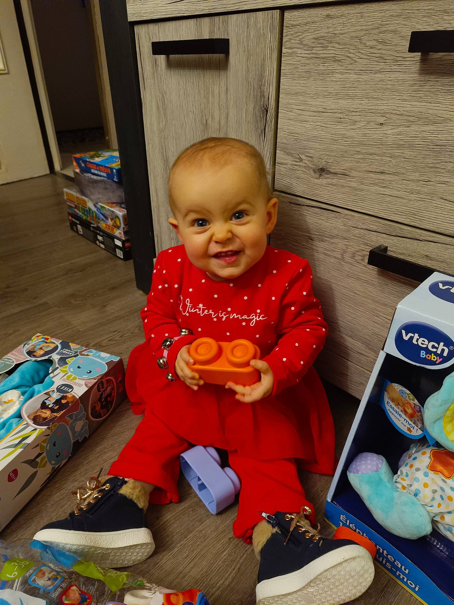 Eloise a rejoint le concours — aidez-le/la à gagner de superbes lots ! baby, baby_toddler_clothing, child, door, flooring, fun, joy, person, play, room, sitting, sleeve, smile, sock, toddler, white, wood