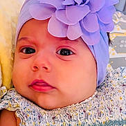 Julia is registered to the contest to win money with this photo: baby, infant, headband, flower, purple, face, eyes, clothing, patterned, blanket, pillow, closeup, skin, cute, young, child, portrait, resting, soft, indoors