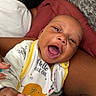 Kyrie Parker is registered to the contest to win money with this photo: baby, smiling, bib, infant, person, arm, closeup, happy, child, fabric, pillow, text, clothing, skin, face, mouth_open, cuddling, indoor, lying_down, parent