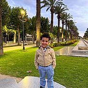 Zayn joined the competition — help win amazing prizes! child, boy, smiling, portrait, outdoor, park, palm_trees, boulevard, garden, grass, walkway, street_lamps, evening, outdoor_lighting, bench, jacket, trousers, shoes, landscape, architecture
