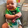 baby, smiling, green_shirt, diaper, baby_chair, monkey_design, rainbow, infant, cute, happy, child, crossed_arms, indoor, person, young_child, comfort, playful, seat, toddler, clothing
