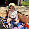 Bodhi joined the competition — help win amazing prizes! toddler, child, wagon, blanket, crocheted, hat, sunhat, outdoor, driveway, toy_car, sandals, shorts, long_sleeve_shirt, grass, trees, sunlight, shadows, plastic_cup, person, summer