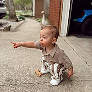 Bodhi joined the competition — help win amazing prizes! toddler, child, pointing, curious, outdoor, driveway, garage, car, clothing, striped_pants, knitted_top, squatting, side_profile, concrete, person, young_child, casual, daylight, expression, curiosity