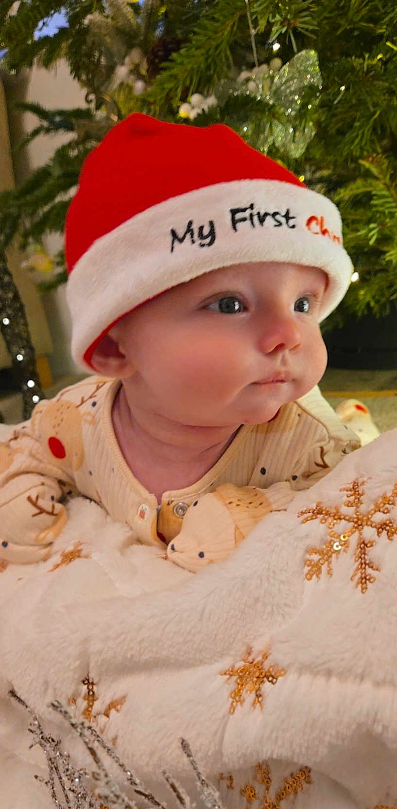 Logan joined the competition — help win amazing prizes! baby, infant, santa_hat, christmas, holiday, pajamas, blanket, snowflake, decorations, christmas_tree, festive, cute, child, face, indoors, cozy, soft_texture, red_hat, sleepwear, holiday_season