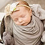 baby, sleeping, swaddled, blanket, headband, flower, teddy_bear, bucket, soft_lighting, portrait, infant, cute, peaceful, cozy, newborn, wrapped, indoor, child, adorable, resting