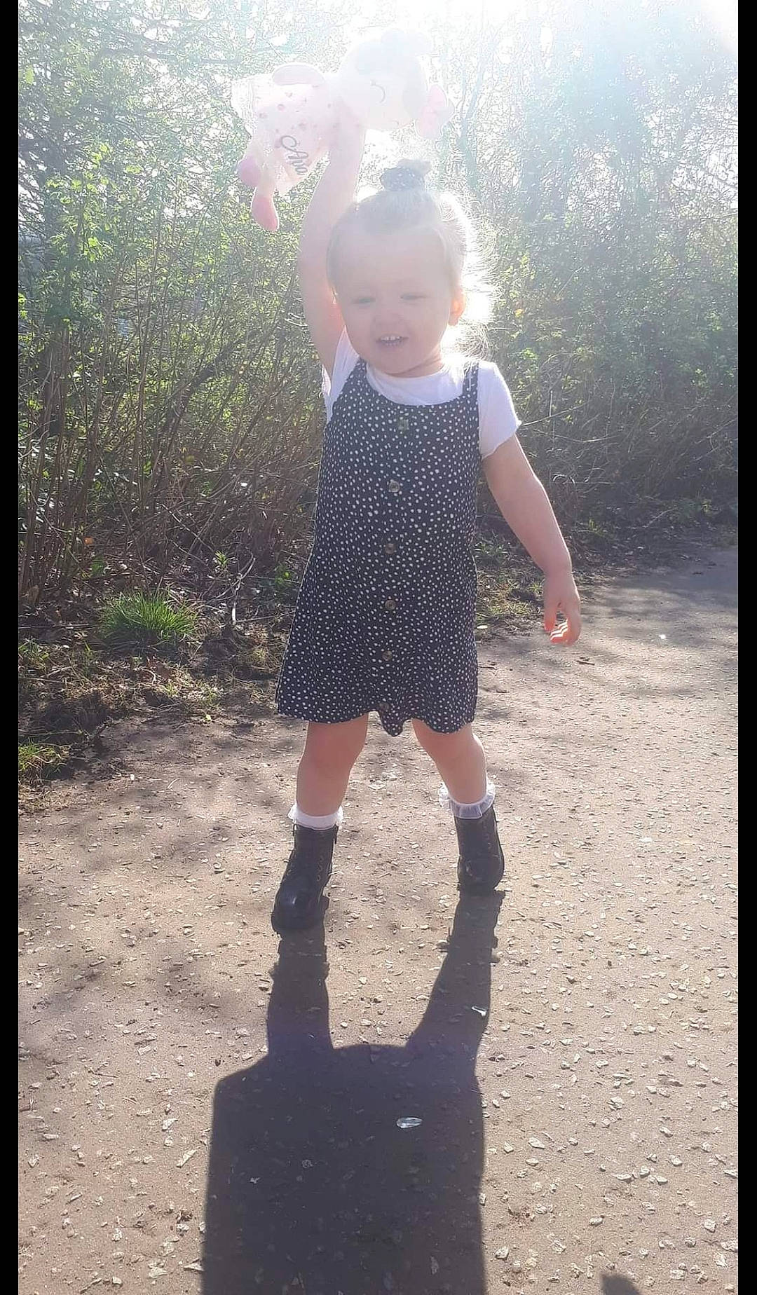 Ava is registered to the contest to win money with this photo: asphalt, baby, baby_toddler_clothing, child, day_dress, dress, fashion_accessory, flash_photography, gesture, grass, happy, human_leg, knee, pattern, people_in_nature, person, road_surface, sleeve, sunlight, tints_and_shades