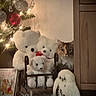 cat, teddy_bears, christmas_tree, ornaments, holiday, festive, indoors, living_room, rocking_chair, stuffed_animals, white_toys, fluffy, longhaired_cat, tabby_cat, green_eyes, portrait, warm_lighting, christmas_lights, carpet, wooden_cabinet