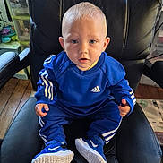 Léon participe au concours pour gagner de l'argent avec cette photo : toddler, child, blue_clothing, adidas, sneakers, nike, sitting, chair, leather_chair, indoor, wooden_floor, toy, storage, curious, person, portrait, baby, face, shoes, casual