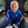 toddler, child, blue_clothing, adidas, sneakers, nike, sitting, chair, leather_chair, indoor, wooden_floor, toy, storage, curious, person, portrait, baby, face, shoes, casual