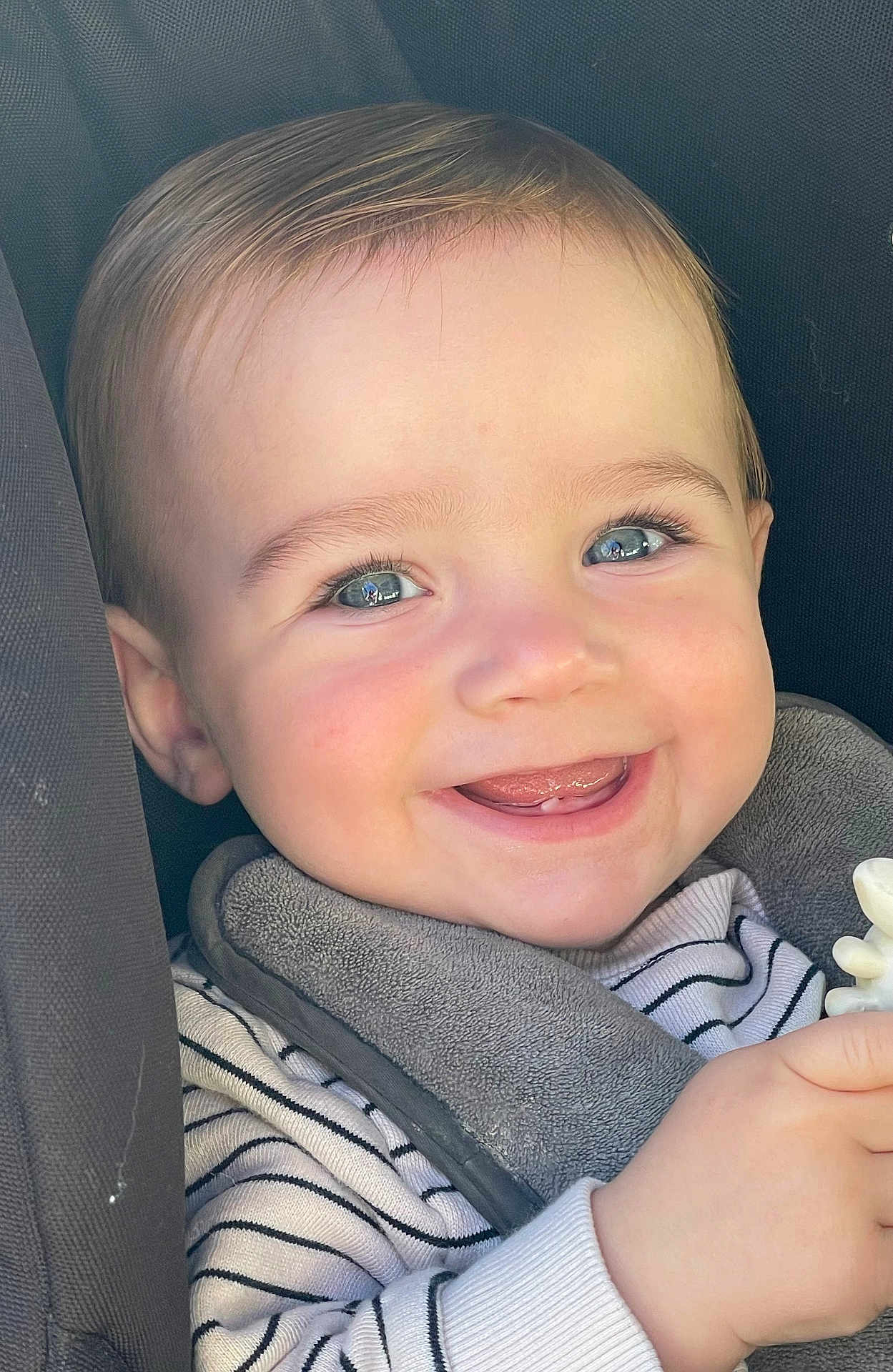 Kevan participe au concours pour gagner de l'argent avec cette photo : baby, child, smiling, face, blue_eyes, striped_clothing, bib, toy, hand, closeup, happy, cute, infant, teeth, skin, person, young_child, seat, car_seat, cozy