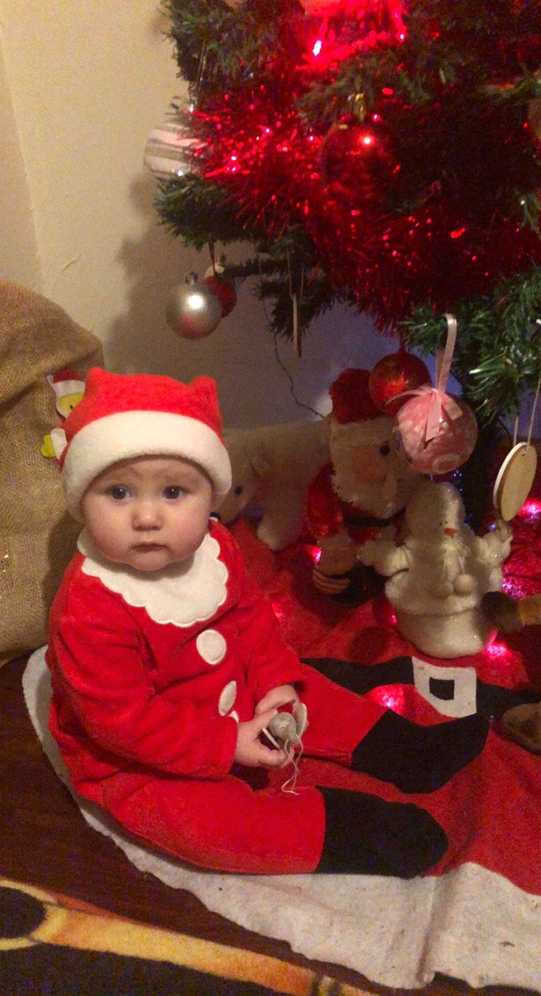 Emy participe au concours pour gagner de l'argent avec cette photo : baby, baby_toddler_clothing, christmas, christmas_decoration, christmas_eve, christmas_ornament, christmas_tree, event, fictional_character, headwear, holiday, holiday_ornament, human_body, lap, ornament, person, red, santa_claus, toddler, toy