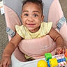 baby, baby_chair, bright_eyes, carpet, child, clothing, colorful, curly_hair, face, furniture, hand, happy, indoor, person, playtime, seat, smiling, toddler, toy, young_child