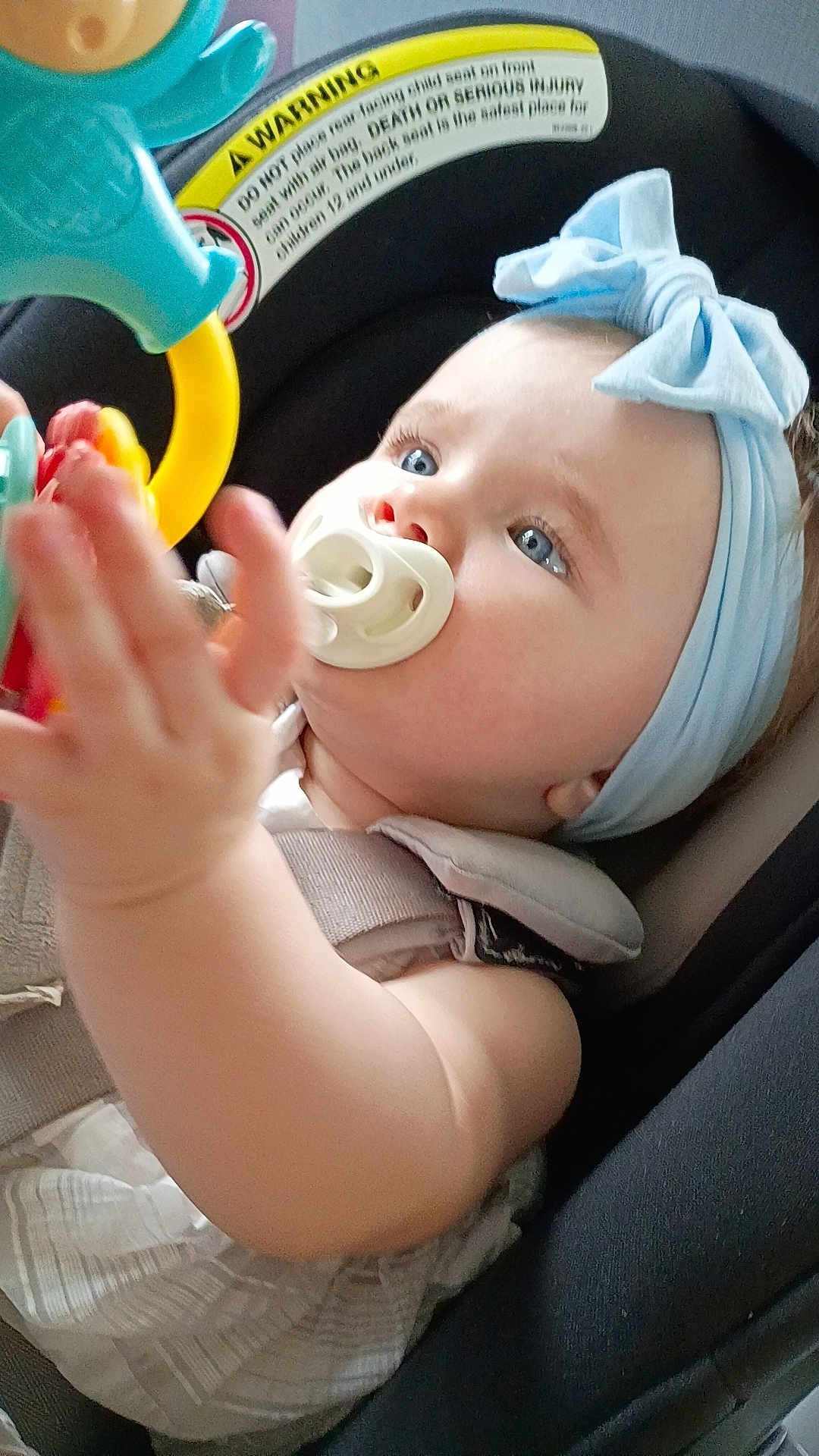 Harley joined the competition — help win amazing prizes! baby, pacifier, headband, blue_eyes, car_seat, toy, hand, harness, warning_label, clothing, child, infant, seatbelt, closeup, indoor, cute, expression, person, accessory, safety