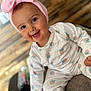 baby, child, smiling, pink_bow, headband, pajamas, strawberry_pattern, sitting, happy, indoors, face, cute, infant, clothing, person, portrait, closeup, soft_texture, wood_floor, playful