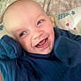 baby, smiling, blue_clothing, blanket, happy, infant, face, cheerful, cute, lying_down, closeup, soft_texture, child, joyful, indoors, skin, head, expression, person, cozy