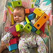 Lucia joined the competition — help win amazing prizes! animal_print, baby, baby_seat, child, colorful, colorful_toys, cute, expression, face, floor, floral_onesie, indoor, infant, patterned_clothing, playtime, sitting, small_child, toy, wooden_blocks, wooden_floor