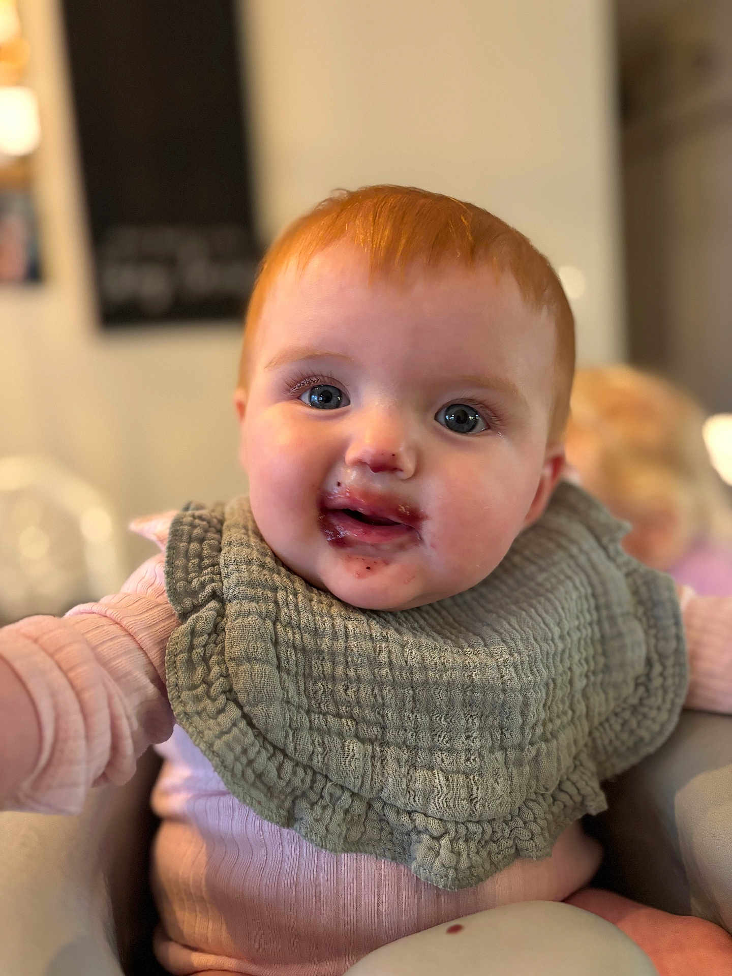 Maisie joined the competition — help win amazing prizes! baby, child, face, bib, messy_face, red_hair, blue_eyes, pink_clothing, indoor, portrait, closeup, highchair, food_stains, cute, smiling, happy, skin, person, infant, young_child