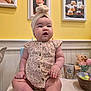 Scotti joined the competition — help win amazing prizes! baby, infant, headwrap, turban, chubby_cheeks, floral_onesie, sitting, table, yellow_wall, picture_frames, framed_photos, stuffed_toy, ceramic_mug, wooden_bowl, colorful_eggs, decorative_frames, smile, portrait, indoor, homedecor