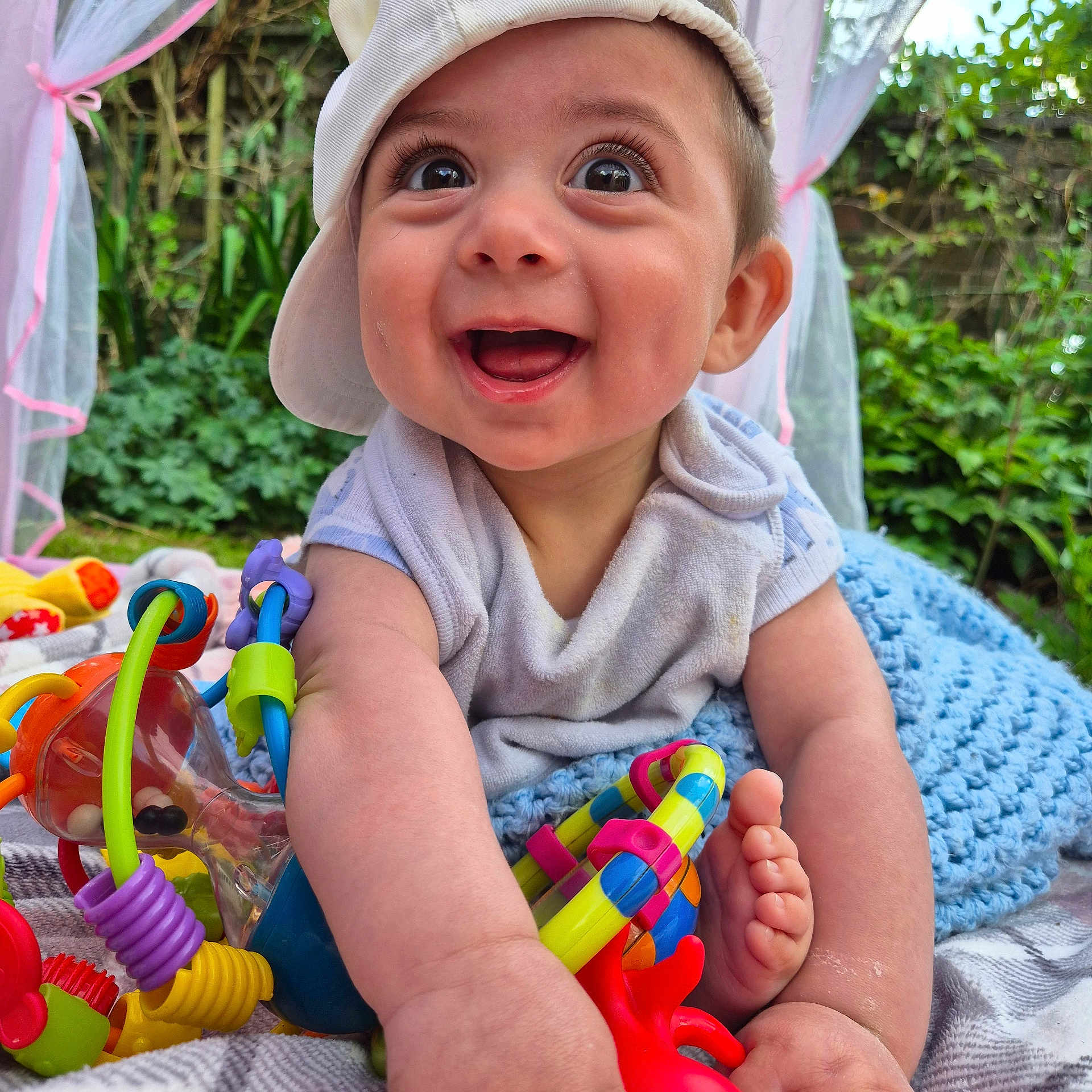 Ario joined the competition — help win amazing prizes! baby, blanket, cap, child, colorful_toy, cute, daylight, face, foot, greenery, hand, happy, infant, nature, outdoor, playful, portrait, skin, smiling, toy