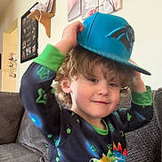 Landyn joined the competition — help win amazing prizes! blue_cap, boy, cap, casual, child, colorful_clothing, comfortable, couch, curly_hair, framed_photos, happy, home_decor, indoor, living_room, playful, portrait, sitting, smiling, wall_art, young_child