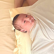 Tasho joined the competition — help win amazing prizes! newborn, baby, blanket, pillow, bed, person, infant, sleeping, wrapped, skin, human_leg, resting, indoors, soft_light, comfort, closeup, portrait, child, cozy, relaxation