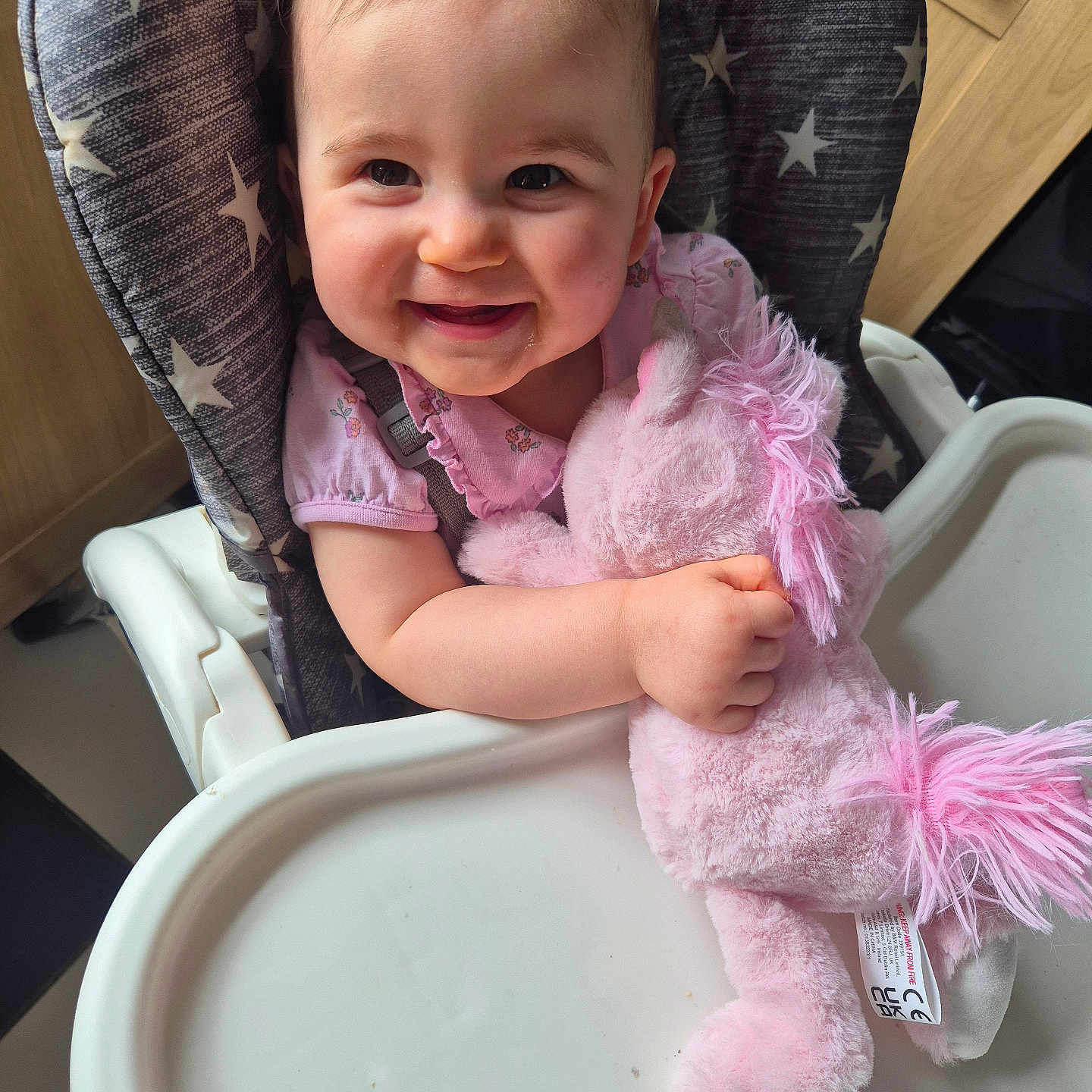 Amelia joined the competition — help win amazing prizes! arm, baby, child, clothing, cute, face, feeding_chair, hair, happy, high_chair, indoor, infant, person, pink, plush_toy, seat, smiling, star_pattern, toy, unicorn