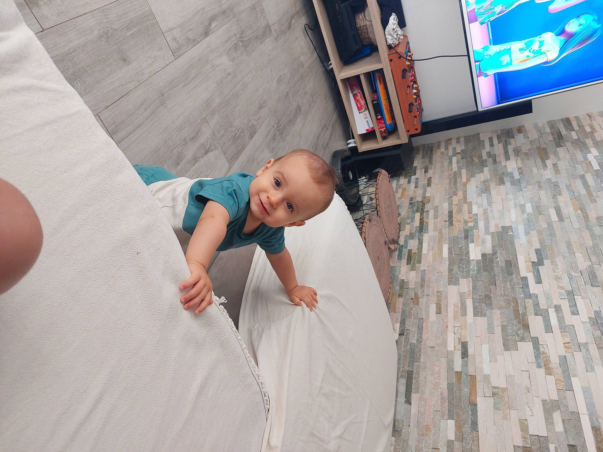 Nathan participe au concours pour gagner de l'argent avec cette photo : baby, baby_toddler_clothing, child, comfort, display_device, floor, flooring, fun, hardwood, human_leg, joy, leg, leisure, linens, person, room, smile, t_shirt, television, television_set