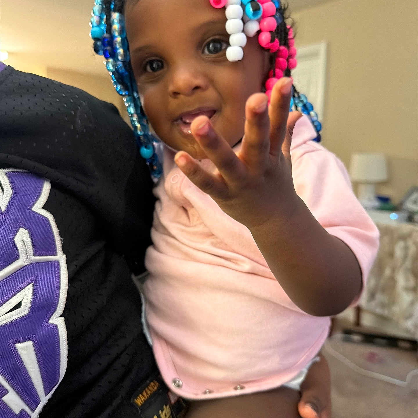 Kreari joined the competition — help win amazing prizes! toddler, child, person, indoor, colorful_beads, hair_beads, pink_shirt, hand, face, smile, curious, holding, seated, home, lamp, furniture, carpet, black_clothing, purple_text, skin