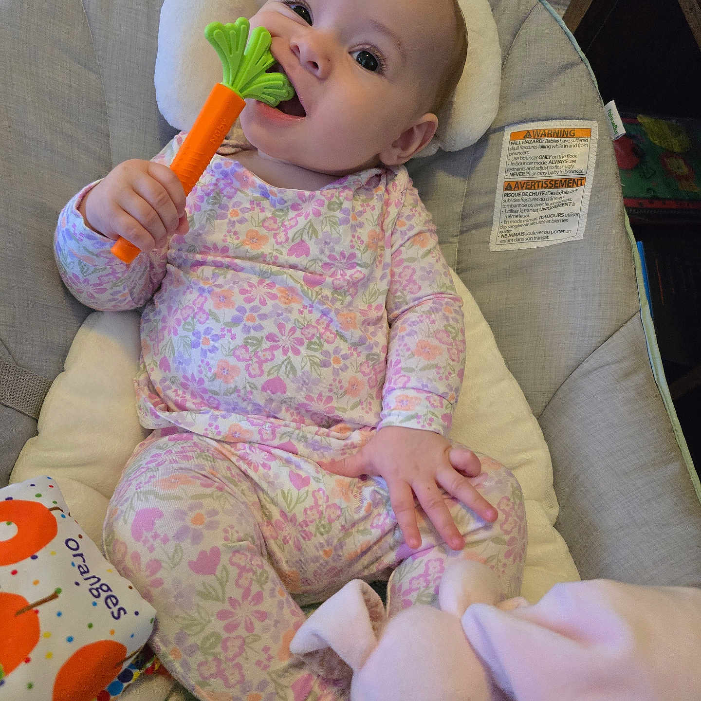 Emilia joined the competition — help win amazing prizes! baby, child, infant, smiling, sitting, portrait, face, eyes, teether, toy, carrot, floral_pajamas, onesie, highchair, cushion, blanket, stuffed_animal, bunny, indoors, happy
