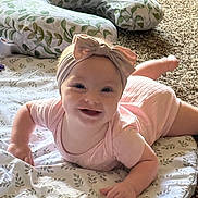 Selyhia is registered to the contest to win money with this photo: baby, infant, smiling, headband, bow, blanket, carpet, pillow, laying_down, happy, cute, child, indoors, soft_lighting, patterned, face, person, apparel, toddler, playtime