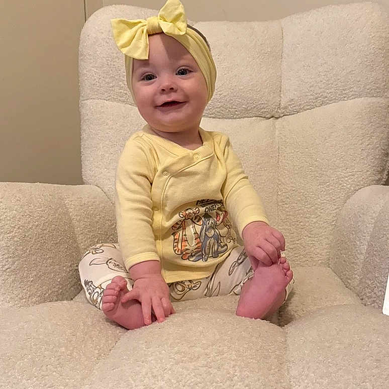 Selyhia is registered to the contest to win money with this photo: armchair, baby, barefoot, bow, child, comfortable, cozy, cute, foot, hand, happy, headband, indoor, infant, person, plush_furniture, portrait, sitting, smiling, yellow_clothing