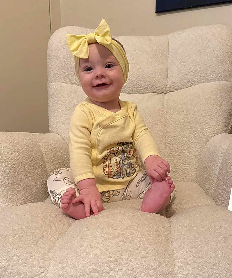 Selyhia is registered to the contest to win money with this photo: baby, child, yellow_clothing, headband, bow, smiling, sitting, armchair, plush_furniture, barefoot, cute, indoor, happy, infant, person, portrait, cozy, comfortable, hand, foot