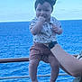 Selyhia is registered to the contest to win money with this photo: baby, child, ocean, sea, sky, headband, bow, shorts, shirt, person, hand, arm, watch, outdoor, happy, smiling, chewing, summer, vacation, cruise