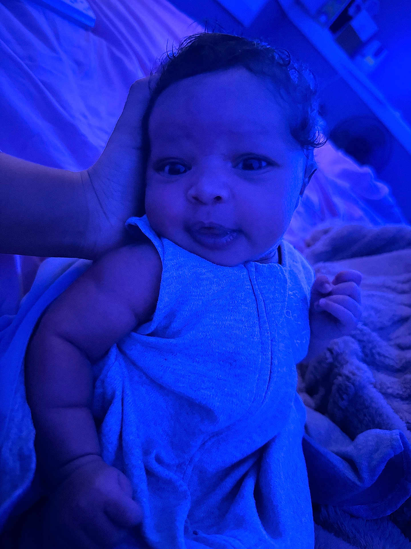Kayomi is registered to the contest to win money with this photo: baby, infant, child, blue_light, blanket, clothing, hand, bed, cozy, cute, portrait, indoor, soft_texture, sleepwear, person, resting, expression, curious, newborn, warm