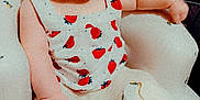 Octavia is registered to the contest to win money with this photo: baby, child, infant, headband, flower, strawberry_pattern, baby_chair, cushion, foot, hand, clothing, indoor, furniture, person, cute, seated, looking_at_camera, soft_lighting, skin, expression
