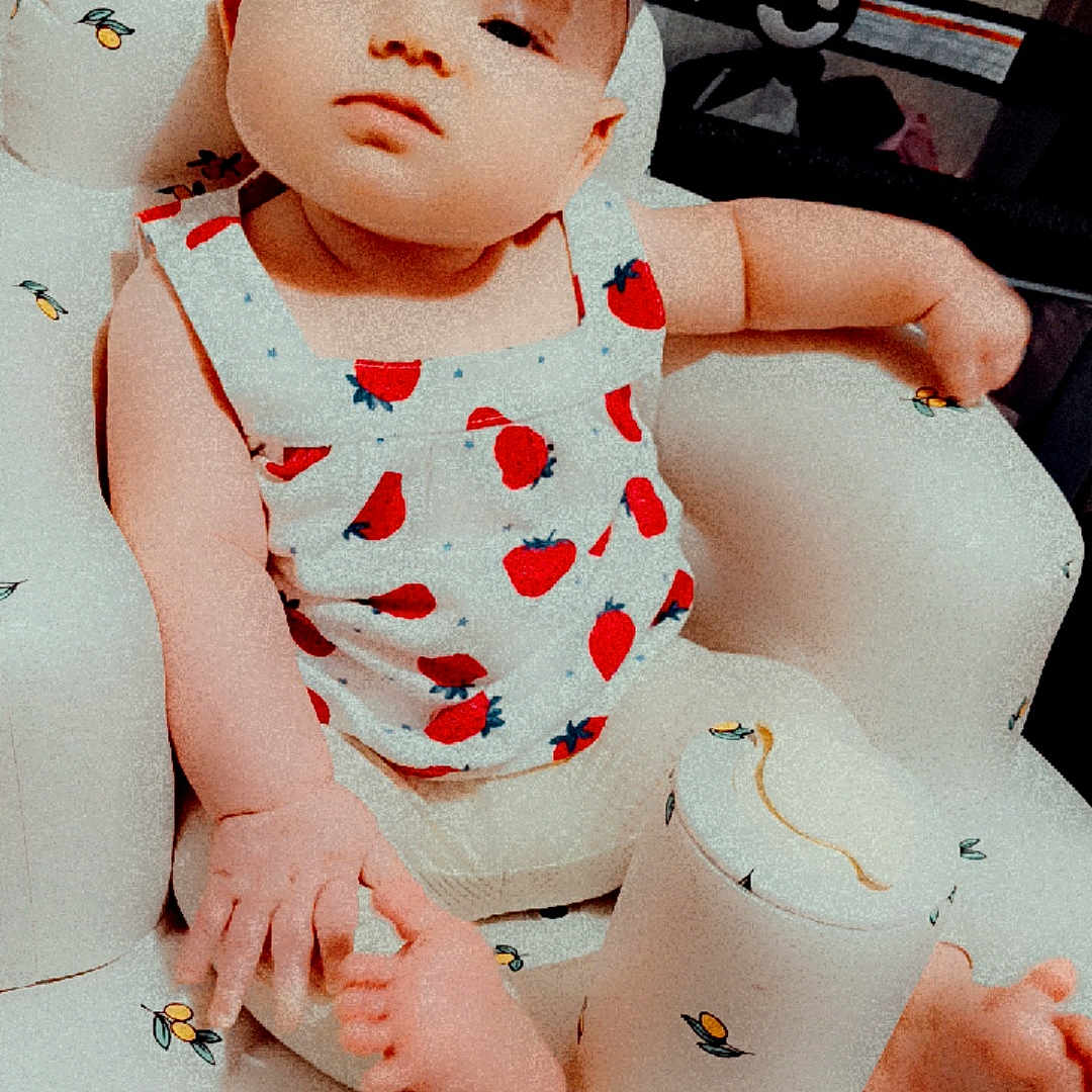 Octavia joined the competition — help win amazing prizes! baby, baby_chair, child, clothing, cushion, cute, expression, flower, foot, furniture, hand, headband, indoor, infant, looking_at_camera, person, seated, skin, soft_lighting, strawberry_pattern