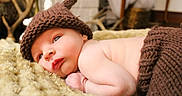 Neyland is registered to the contest to win money with this photo: baby, infant, knitted_hat, brown_clothing, blanket, lying_down, closeup, soft_texture, indoors, cuteness, newborn, face, skin, hand, peaceful, warmth, portrait, child, resting, cozy