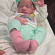 Marilyn is registered to the contest to win money with this photo: baby, newborn, infant, sleeping, hand, headband, bow, pink_socks, pastel_clothing, blanket, hand_support, couch, indoor, person, cute, peaceful, small_hand, soft_texture, relaxed, resting