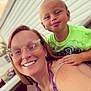 Matteo is registered to the contest to win money with this photo: woman, child, smile, glasses, outdoor, portrait, casual, purple_top, neon_green_shirt, playful, table, house_siding, daylight, happy, people, shoulder, hand, face, person, together