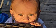 Matteo joined the competition — help win amazing prizes! toddler, child, face, eyes, hands, table, wicker, glass, outdoor, wooden_deck, toy, sunlight, shadow, curious, peek, baby, playful, green_eyes, close_up, daylight