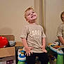 Tucker joined the competition — help win amazing prizes! child, smiling, indoor, toy, piano, colorful, mirror, reflection, cardboard_box, clothing, tshirt, pants, playful, furniture, happy, person, young, blonde_hair, seated, floor