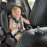 Denver is registered to the contest to win money with this photo: child, car_seat, smiling, vehicle_interior, seatbelt, black_leather, headrest, window, daylight, casual_clothing, young_boy, safety_harness, car, seat, blonde_hair, happy, portrait, indoor, person, travel