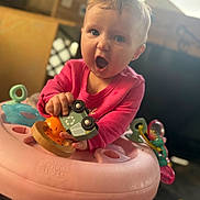 Angel joined the competition — help win amazing prizes! baby, child, pink_clothing, baby_walker, toy_car, indoor, floor_mat, wooden_toy, expression, face, hand, playtime, colorful_toys, mouth_open, infant, person, cute, early_childhood, bright, soft_light