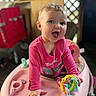 baby, child, pink_clothing, walker, toy, colorful, smiling, happy, indoor, face, hand, playtime, cute, young, infant, bright, expression, seated, plastic, person