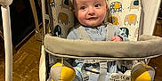 Caleb is registered to the contest to win money with this photo: baby, infant, baby_swing, elephant_pattern, toy, indoor, floor, clothing, white_socks, straps, seat, curtain, wood_floor, play, child, person, cute, smile, expression, sitting