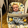 baby, infant, baby_swing, elephant_pattern, toy, indoor, floor, clothing, white_socks, straps, seat, curtain, wood_floor, play, child, person, cute, smile, expression, sitting