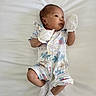 baby, child, clothing, cute, face, floral_pattern, head, human, infant, limbs, lying_down, mittens, newborn, portrait, resting, romper, skin, small, socks, white_background