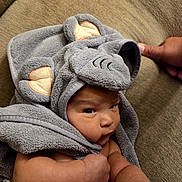 Maxímo is registered to the contest to win money with this photo: baby, towel, elephant_ears, infant, couch, arm, thumb, face, skin, cute, child, wrapped, soft, fabric, indoors, person, expression, cozy, texture, closeup