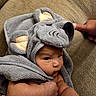 baby, towel, elephant_ears, infant, couch, arm, thumb, face, skin, cute, child, wrapped, soft, fabric, indoors, person, expression, cozy, texture, closeup