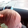 car_interior, casual, child, close_up, clothing, cute, dashboard, flower, hair, indoors, natural_light, overexposed, person, profile, seat, side_view, skin, toy, window, young_child